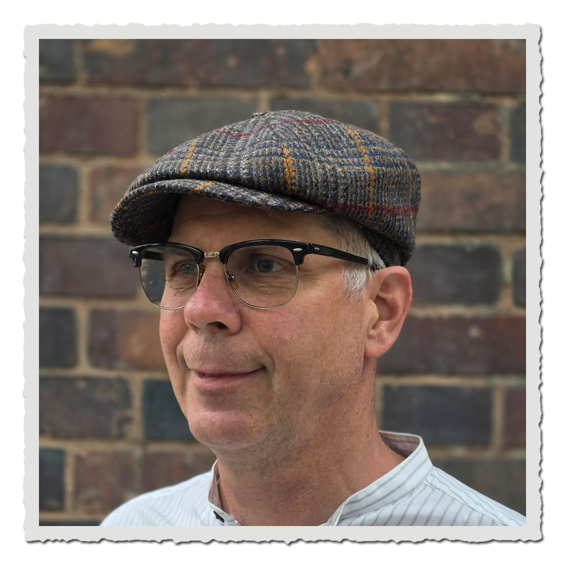 Vorderansicht einer klassischen Ballonmütze JJ Hats aus Harris Tweed. Die Mütze ist in 8-Panel-Form gearbeitet und zeigt ein auffälliges Karomuster in Blau-, Grau- und Brauntönen mit roten und gelben Akzenten.