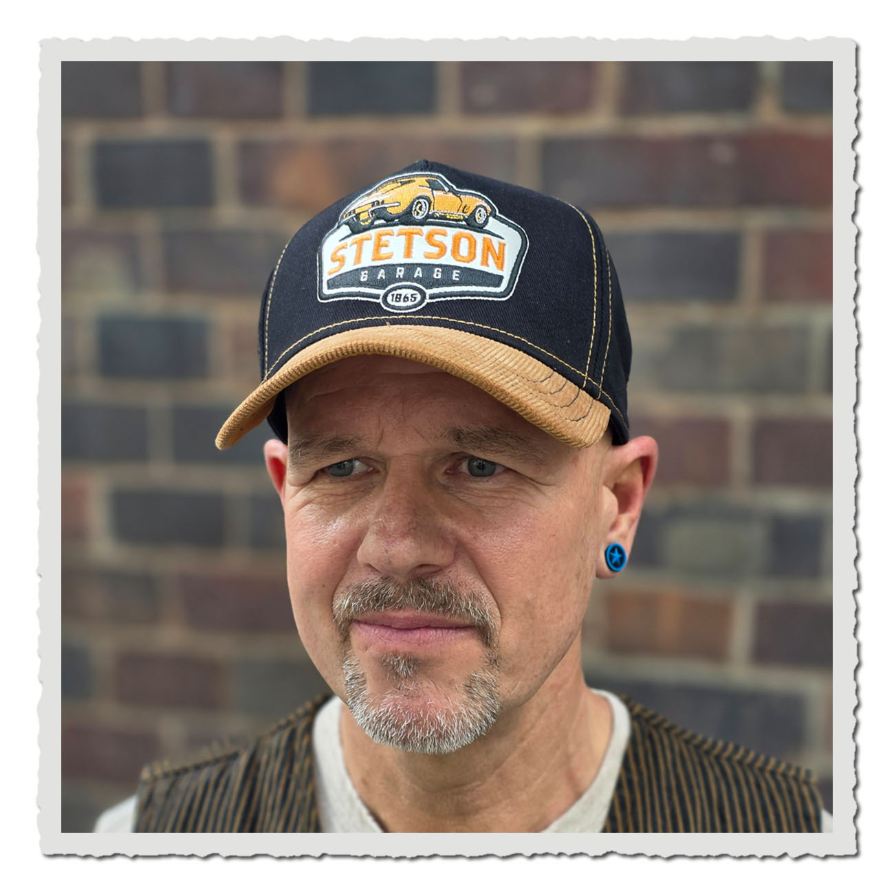Mann trägt eine Stetson Trucker Cap Piston in Orange-Blau mit Happy-Piston-Stickerei